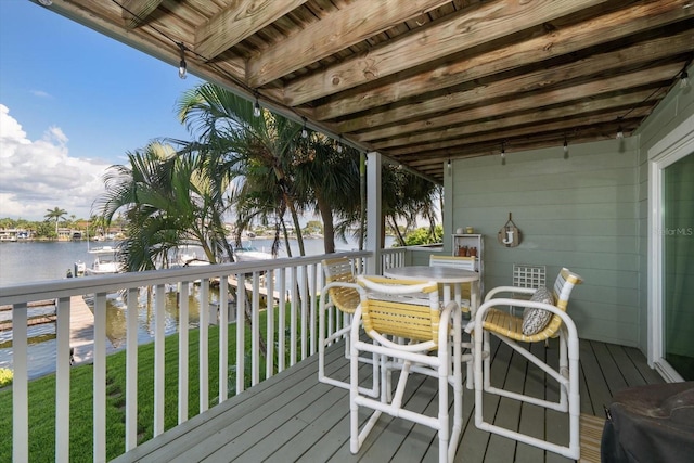 wooden terrace featuring a water view and a yard