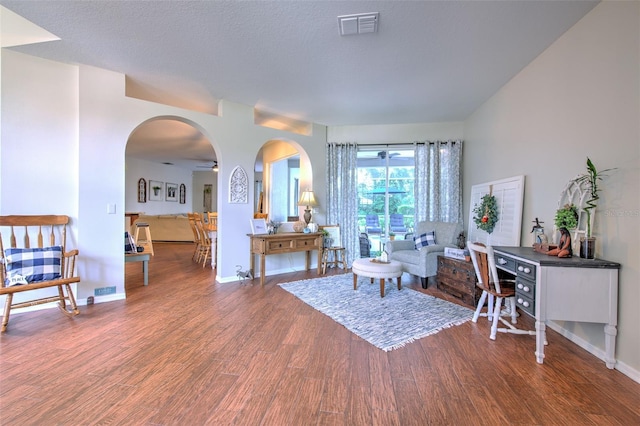 living room featuring ceiling fan, dark wood-type flooring, and a textured ceiling