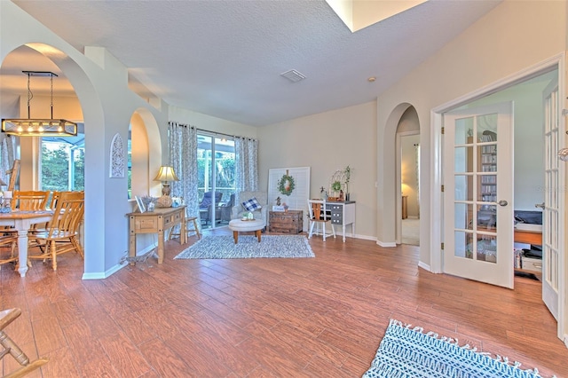 living room featuring wood-type flooring, a textured ceiling, and french doors