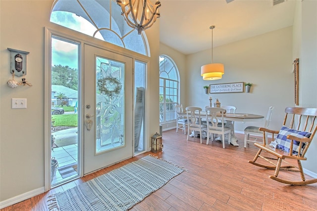 foyer entrance featuring an inviting chandelier, plenty of natural light, and hardwood / wood-style floors