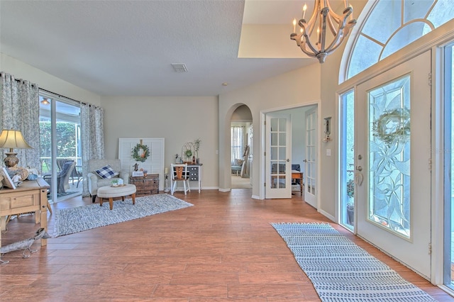 foyer with french doors, hardwood / wood-style flooring, a notable chandelier, and a textured ceiling