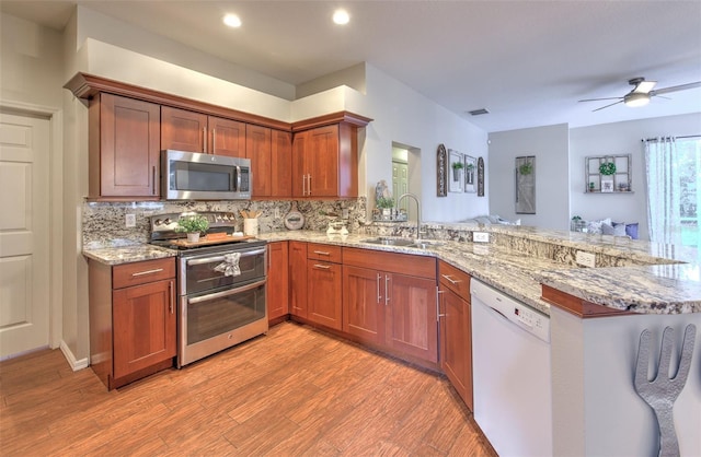 kitchen featuring sink, kitchen peninsula, light hardwood / wood-style flooring, appliances with stainless steel finishes, and ceiling fan