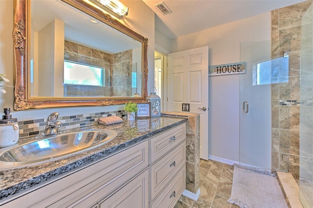 bathroom featuring a textured ceiling, tasteful backsplash, vanity, and an enclosed shower