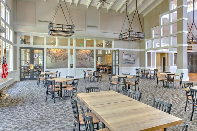 dining room with beamed ceiling, carpet flooring, and high vaulted ceiling