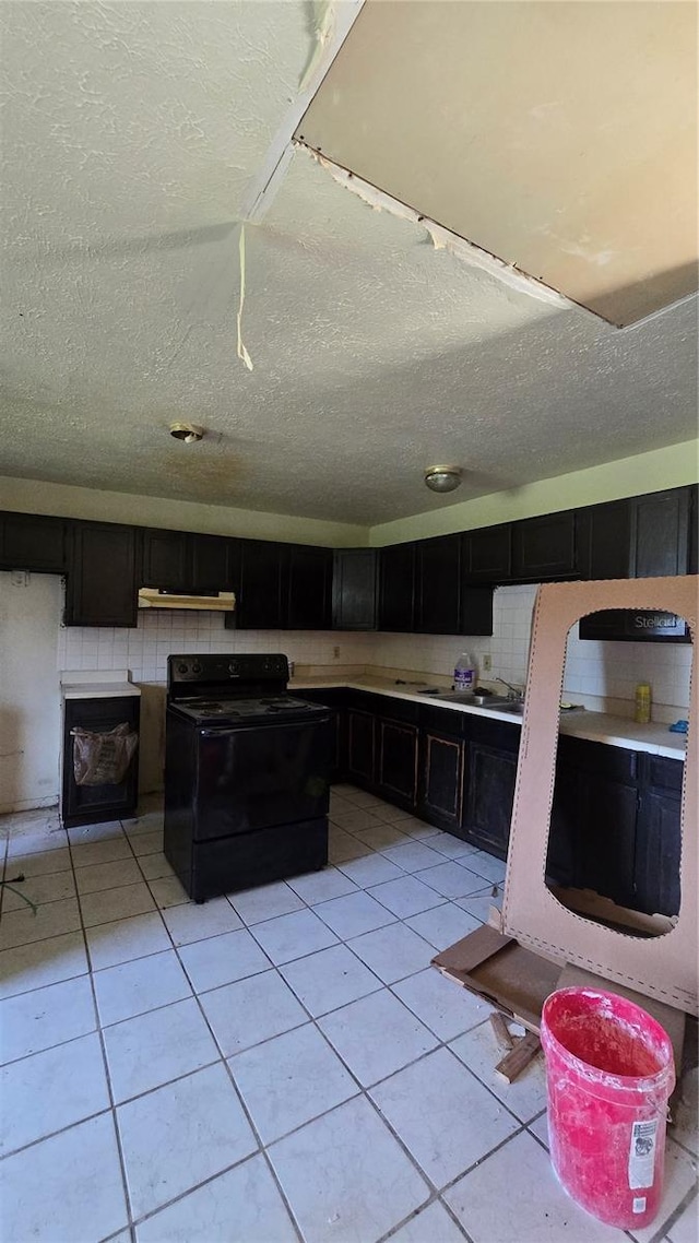 kitchen with a textured ceiling, light tile patterned flooring, and black range with electric cooktop