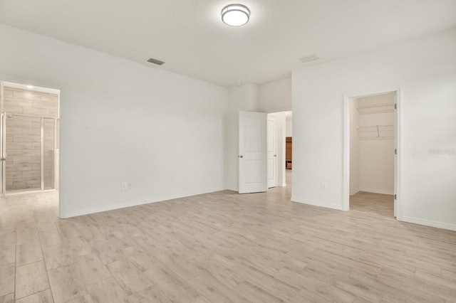 unfurnished bedroom with a spacious closet, light hardwood / wood-style floors, and a closet