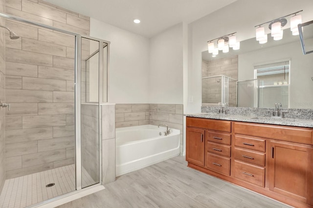 bathroom featuring wood-type flooring, vanity, and separate shower and tub