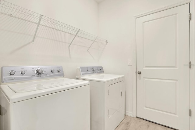 laundry room with washer and clothes dryer and light hardwood / wood-style flooring