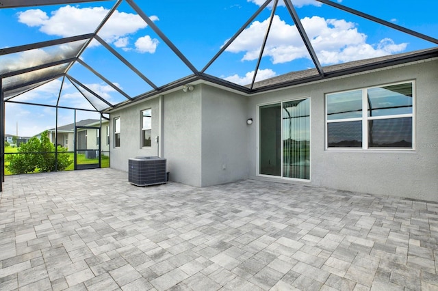 exterior space with glass enclosure, cooling unit, and a patio area