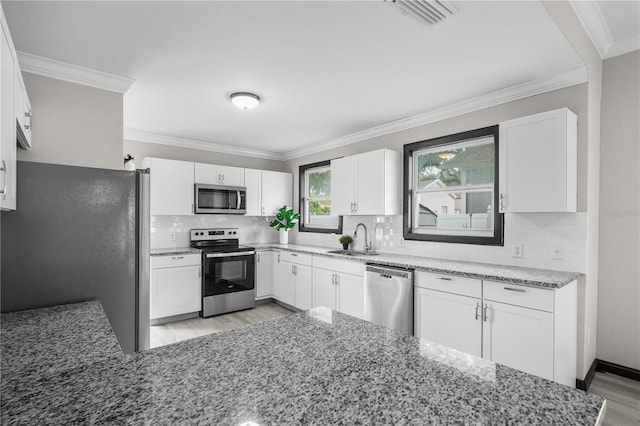 kitchen with white cabinets, appliances with stainless steel finishes, tasteful backsplash, and light hardwood / wood-style flooring