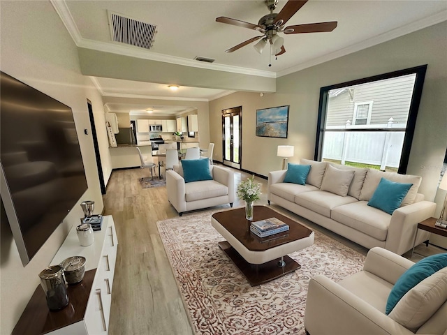 living room with ornamental molding, a healthy amount of sunlight, and light hardwood / wood-style floors