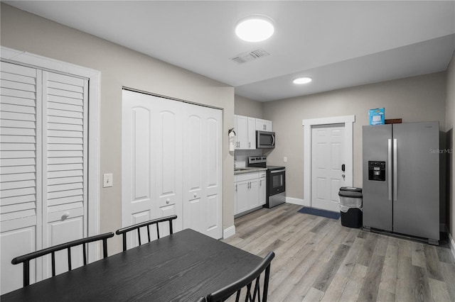 kitchen featuring white cabinets, stainless steel appliances, and light wood-type flooring