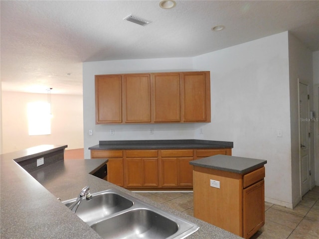 kitchen featuring light tile patterned floors, hanging light fixtures, sink, and a kitchen island