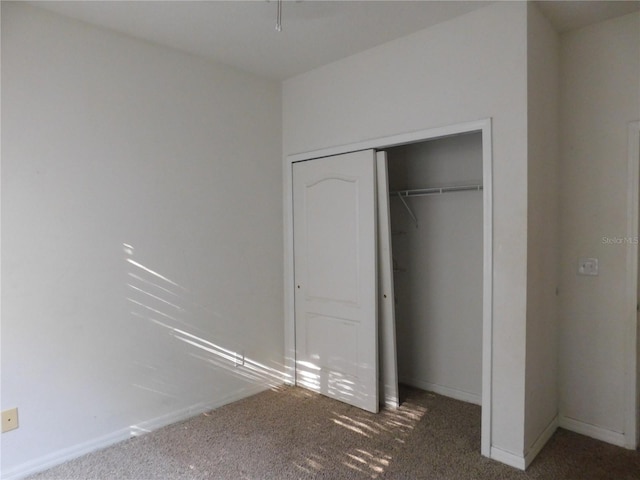 unfurnished bedroom with dark colored carpet and a closet