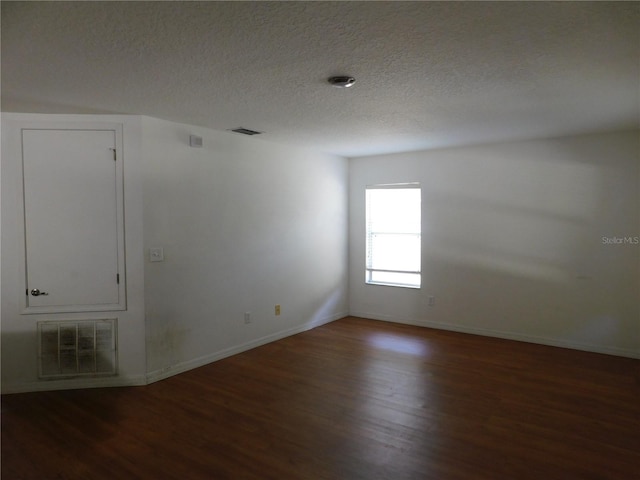 spare room featuring a textured ceiling and dark hardwood / wood-style flooring