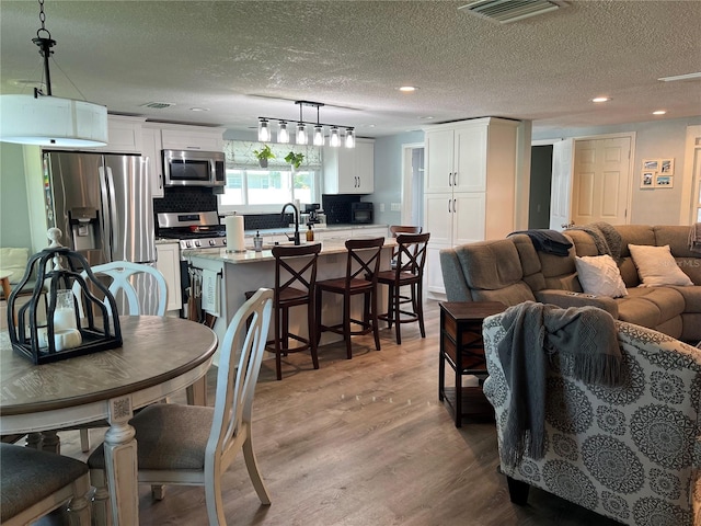 dining room with a textured ceiling, sink, and light hardwood / wood-style flooring