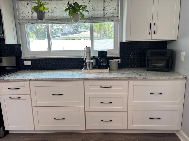 kitchen featuring decorative backsplash, light stone counters, white cabinetry, and dark hardwood / wood-style flooring