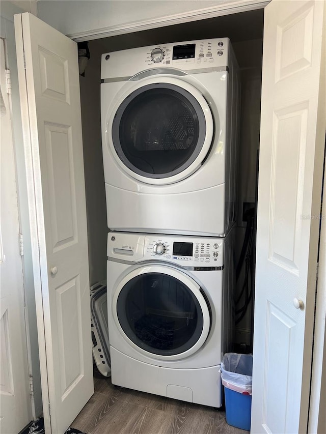 laundry area with dark hardwood / wood-style floors and stacked washer / drying machine