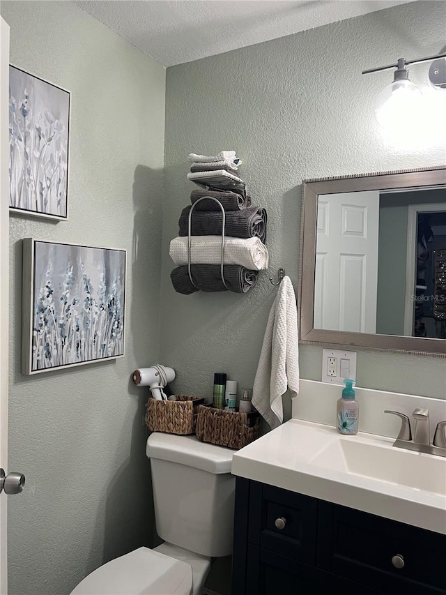 bathroom featuring a textured ceiling, vanity, and toilet