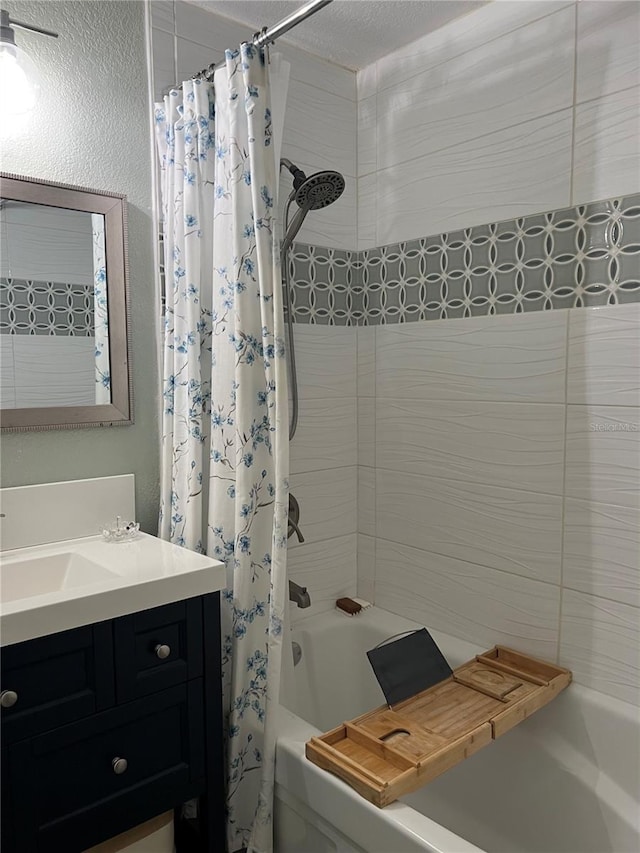 bathroom featuring a textured ceiling, shower / tub combo with curtain, and vanity