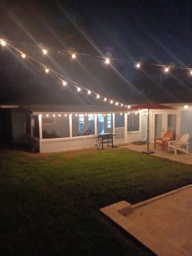 back house at twilight with a lawn and a patio