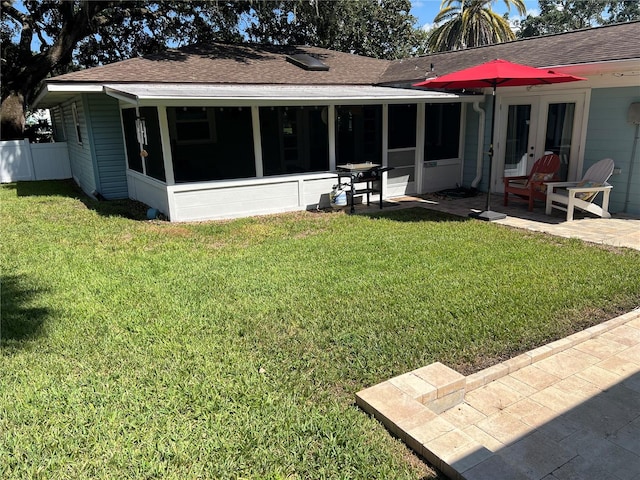 rear view of house with a patio, a yard, a sunroom, and french doors