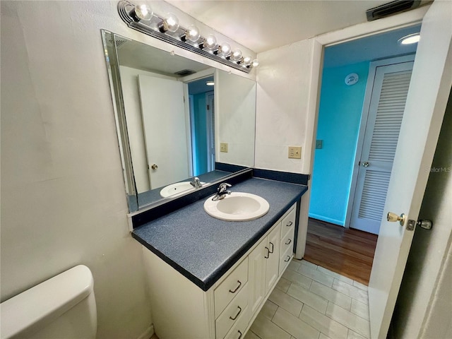 bathroom with toilet, vanity, and hardwood / wood-style flooring