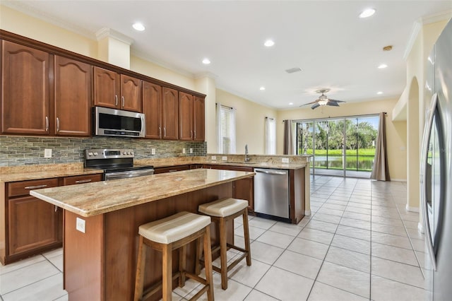 kitchen featuring a kitchen bar, appliances with stainless steel finishes, light tile patterned floors, and a kitchen island