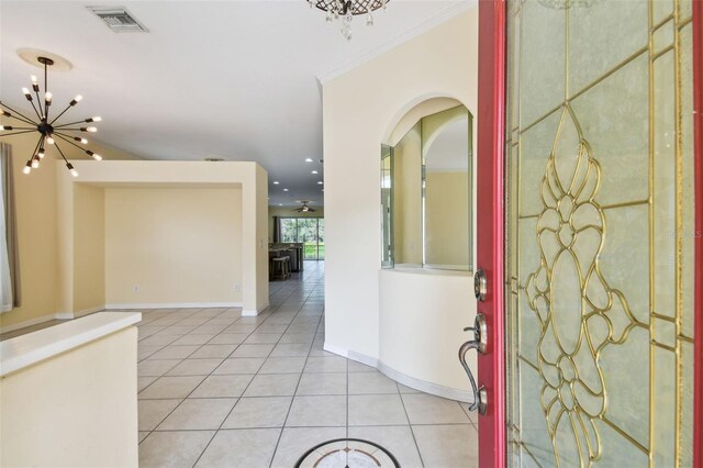 entrance foyer featuring crown molding, light tile patterned floors, and an inviting chandelier