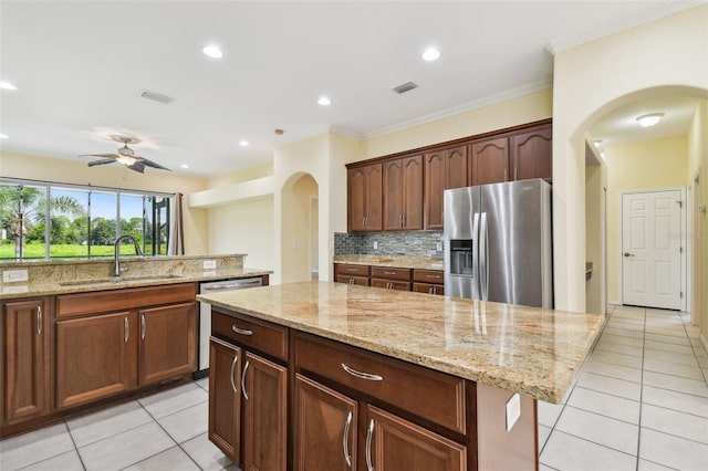 kitchen with ceiling fan, sink, a center island, stainless steel appliances, and light tile patterned floors