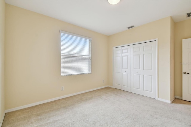 unfurnished bedroom with a closet and light colored carpet