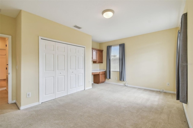 unfurnished bedroom with light carpet and a closet