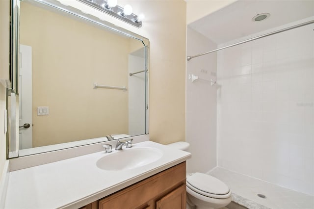 bathroom with tiled shower, vanity, and toilet