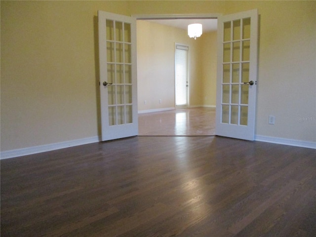 unfurnished room with dark hardwood / wood-style floors, a chandelier, and french doors