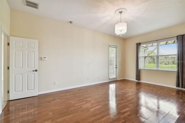 spare room featuring a chandelier and wood-type flooring