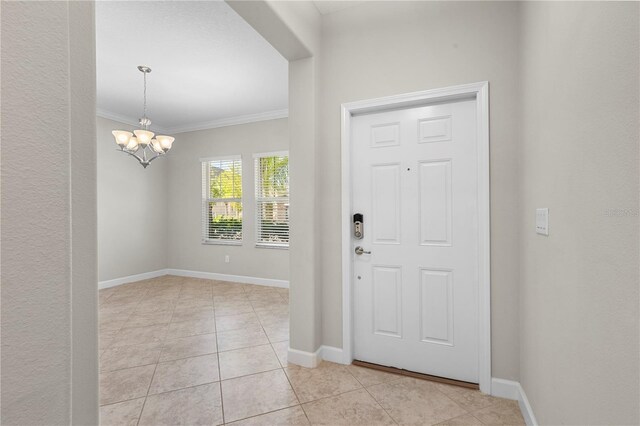 foyer with an inviting chandelier, crown molding, light tile patterned flooring, and baseboards