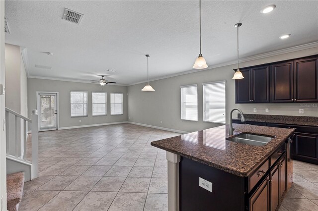 kitchen with dark brown cabinets, sink, crown molding, and an island with sink