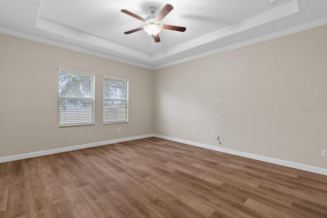 unfurnished room with ceiling fan, hardwood / wood-style floors, a tray ceiling, and crown molding