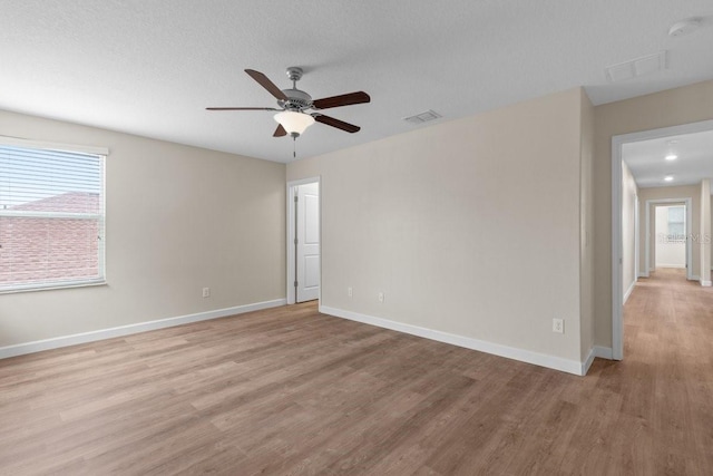 empty room with ceiling fan and light hardwood / wood-style floors