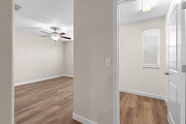 hall featuring a textured ceiling and light hardwood / wood-style flooring