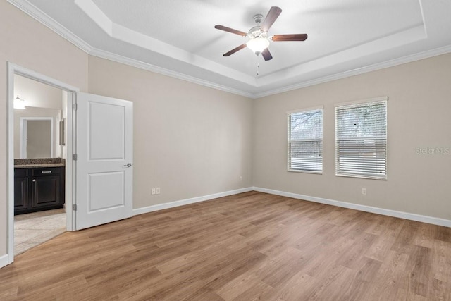 spare room with light hardwood / wood-style floors, a tray ceiling, and ceiling fan