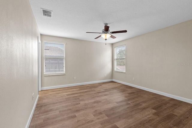 spare room featuring ceiling fan, wood-type flooring, and a textured ceiling