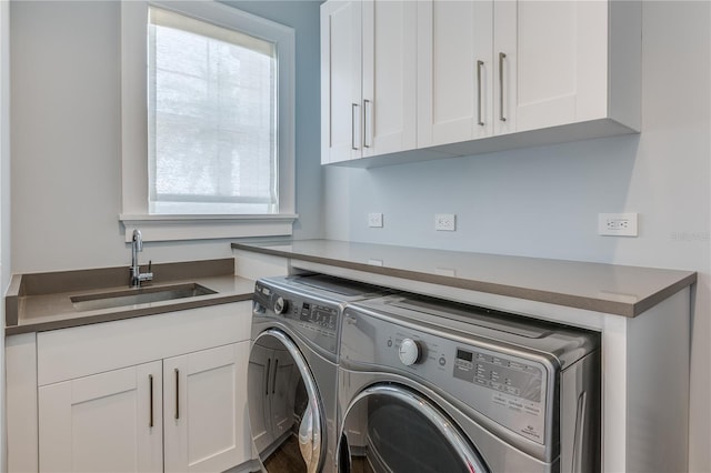 clothes washing area featuring washing machine and dryer, sink, and cabinets