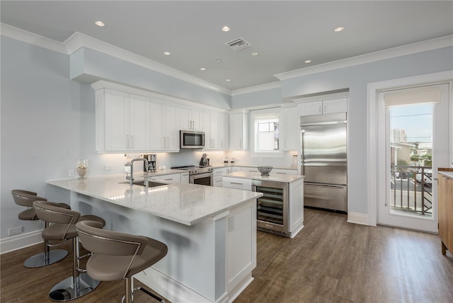 kitchen featuring sink, kitchen peninsula, white cabinetry, appliances with stainless steel finishes, and dark hardwood / wood-style flooring