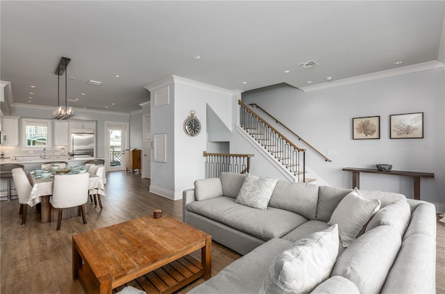 living room featuring wood-type flooring, a chandelier, and crown molding