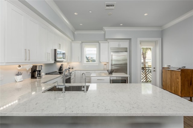 kitchen with appliances with stainless steel finishes, crown molding, light stone counters, and white cabinets