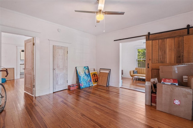 misc room featuring ornamental molding, ceiling fan, hardwood / wood-style flooring, and a barn door