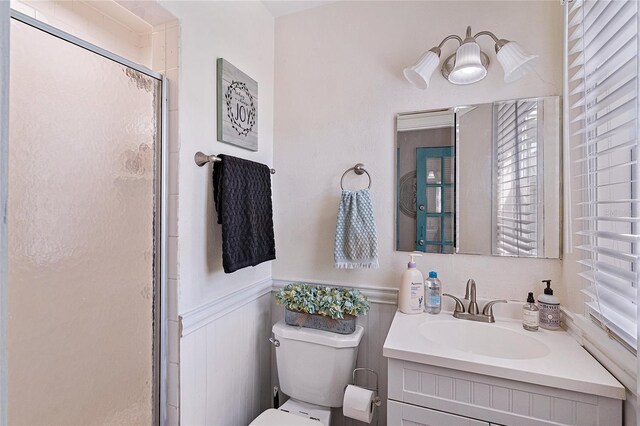 bathroom with a wealth of natural light, vanity, toilet, and a shower with shower door