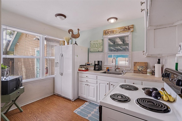 kitchen featuring white cabinets, sink, white appliances, and a wealth of natural light