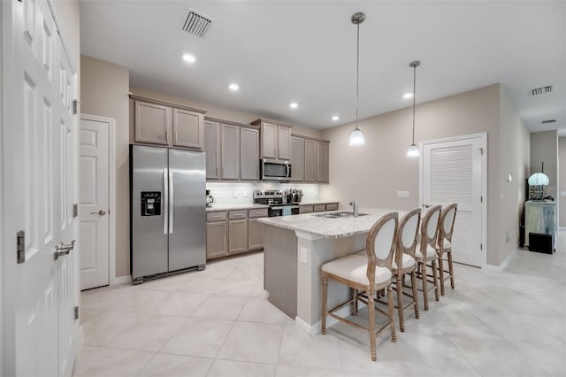 kitchen with a kitchen island with sink, tasteful backsplash, hanging light fixtures, a kitchen breakfast bar, and stainless steel appliances